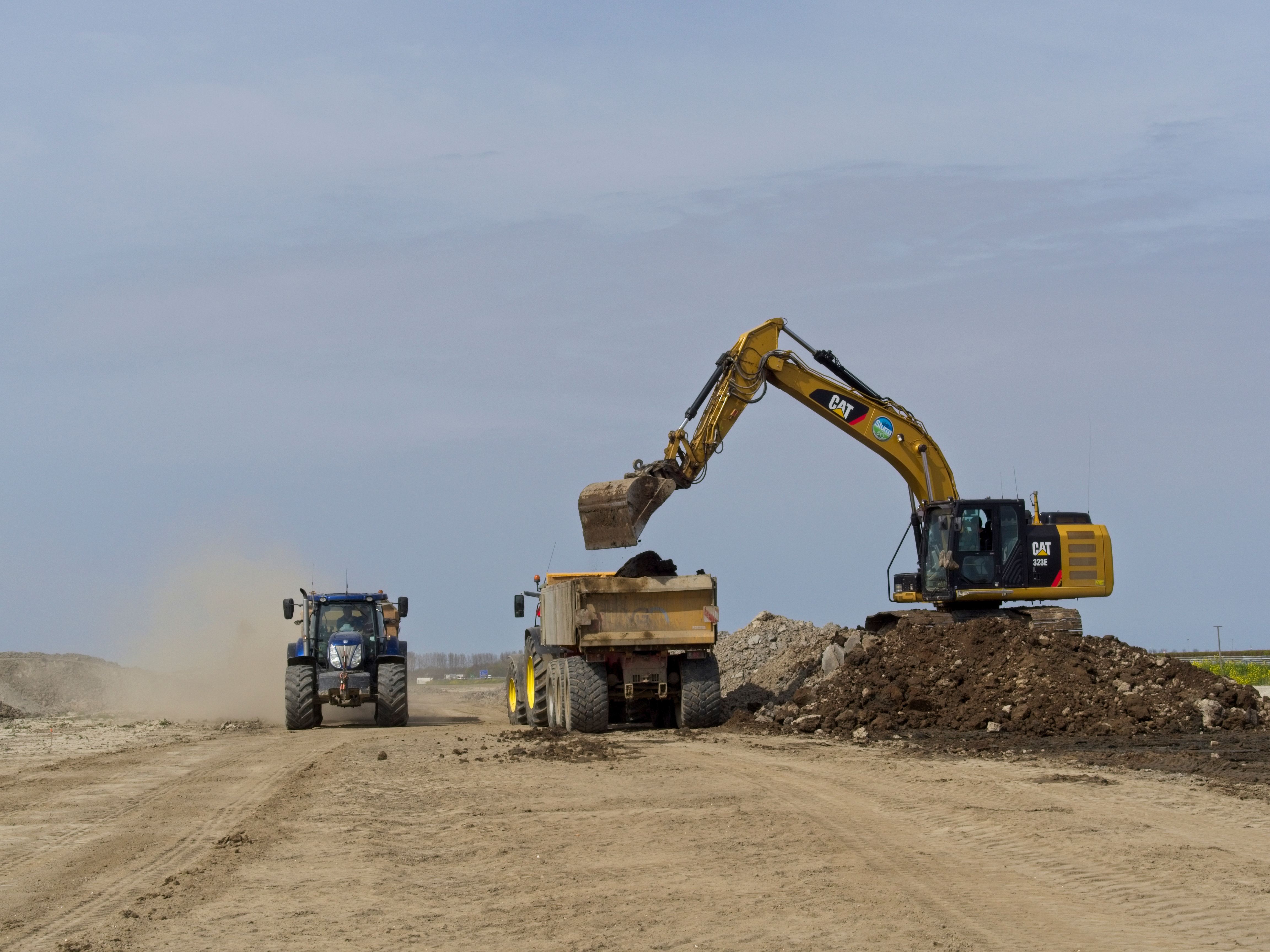 CAT excavator loading earth into a trailer on a construction site